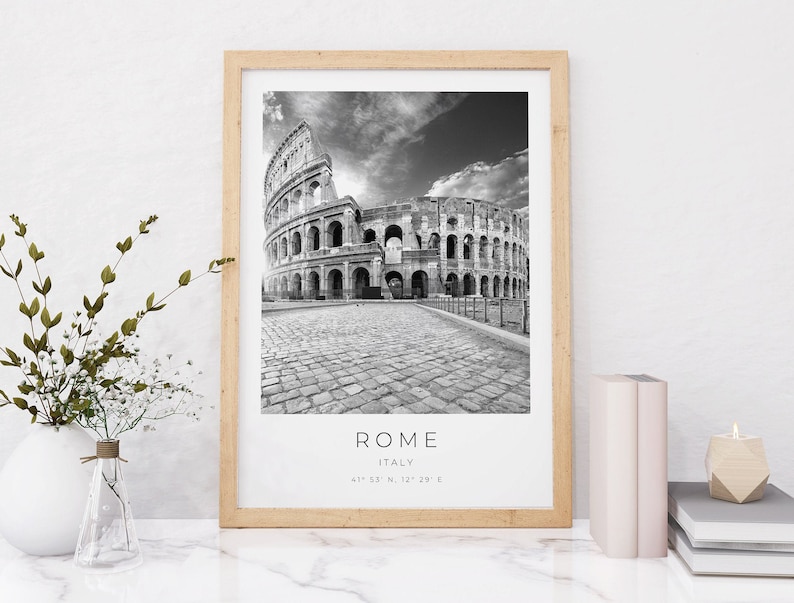 May include: Black and white photograph of the Colosseum in Rome, Italy. The image is framed in a light wood frame. The text "ROME" is printed below the image, along with "ITALY" and the coordinates "41&deg; 53' N, 12&deg; 29' E".