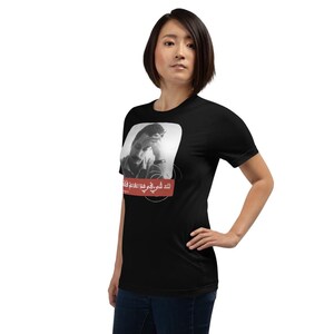 May include: Black t-shirt with a black and white photo of a man with a quote in Arabic script that reads "لك في اللهِ مَوْعِدٌ لاَ يُخْلَفُ" which translates to "You have a promise with God that will not be broken."