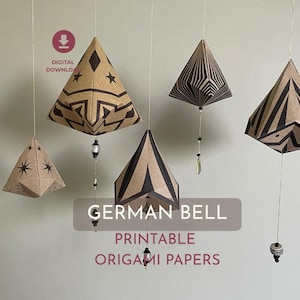 May include: Origami bells in brown paper with black geometric patterns suspended by gold threads. The text "GERMAN BELL PRINTABLE ORIGAMI PAPERS" is displayed on a grey background. A digital download icon is in the upper left corner.