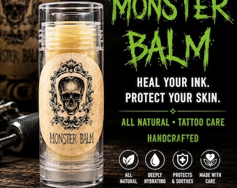 Puede incluir: Un tubo de plástico transparente con bálsamo amarillo para tatuajes y una etiqueta ovalada beige con un cráneo negro en un marco ornamentado. El texto dice MONSTER BALM, HEAL YOUR INK. PROTECT YOUR SKIN. ALL NATURAL TATTOO CARE.
