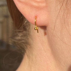 May include: A gold hoop earring with a small ball at the end.
