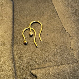 May include: A pair of gold hoop earrings with a small ball at the end of each hoop.