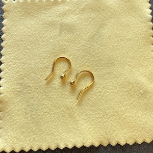 May include: Two gold-colored earring hooks with a small ball at the end of each hook.