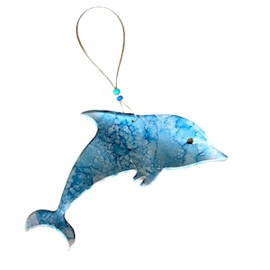 May include: A blue and white dolphin ornament with a string for hanging. The dolphin is painted with a marbled effect.