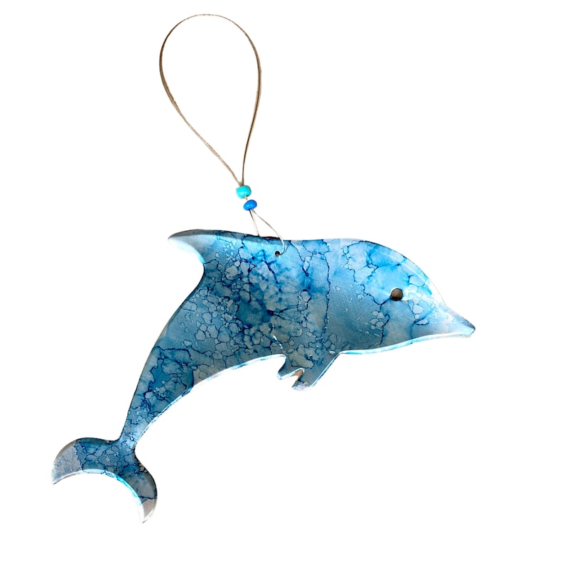 May include: A blue and white dolphin ornament with a string for hanging. The dolphin is painted with a marbled effect.