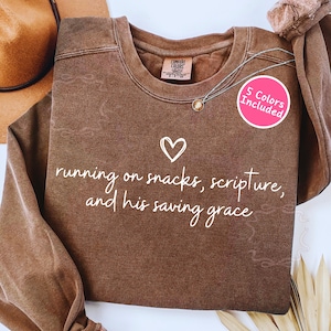 May include: A white ceramic mug with a black handle and the text "But First, Coffee" in a black, handwritten-style font. The mug is on a white surface.