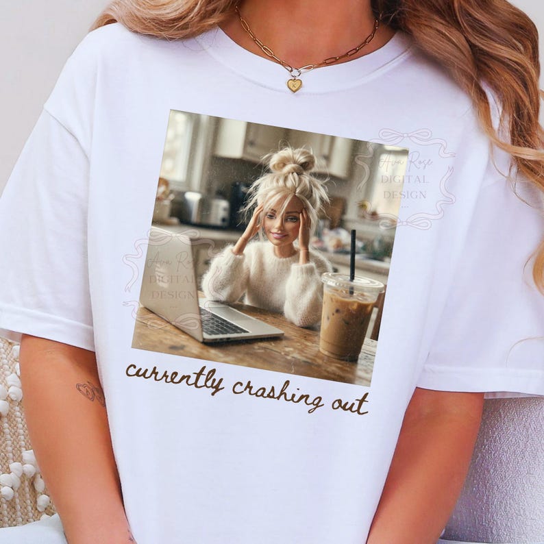 Peut inclure: T-shirt blanc avec une image encadr&eacute;e d'une femme blonde, un ordinateur portable et une boisson au caf&eacute;. Le texte "currently crashing out" est en dessous de l'image. Le t-shirt est un v&ecirc;tement d&eacute;contract&eacute; de tous les jours.