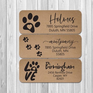 May include: Three brown kraft paper address labels with black paw print designs. The labels have the names Holmes, montgomery, and Birmingham with addresses printed below.