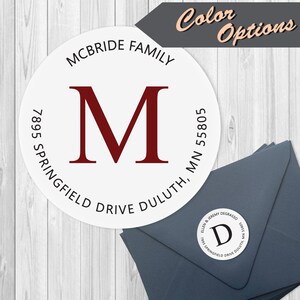 May include: A white round return address label with black text and a red letter "M" in the center. The text reads "MCBRIDE FAMILY 7895 SPRINGFIELD DRIVE DULUTH, MN 55805".