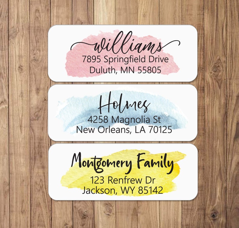 May include: Three watercolour-style address labels with white backgrounds and black text. The top label is pink and says "Williams, 7895 Springfield Drive, Duluth, MN 55805". The middle label is blue and says "Holmes, 4258 Magnolia St, New Orleans, LA 70125". The bottom label is yellow and says "Montgomery Family, 123 Renfrew Dr, Jackson, WY 85142".