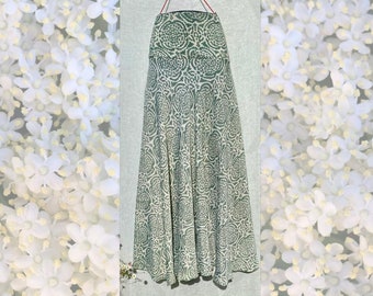 May include: A long, flowing green skirt with a white floral pattern. The skirt has a simple, gathered waist and a flowing, A-line silhouette.