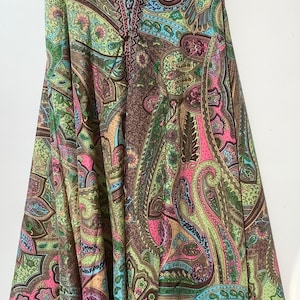 May include: A long, flowing skirt with a paisley print in shades of brown, green, pink, and blue. The skirt has a wide waistband and a flowing, A-line silhouette.