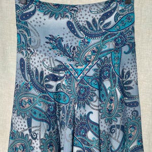 May include: A blue and white paisley print skirt with a high waist. The skirt is made of a soft, flowing fabric.