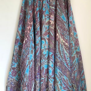 May include: A long, flowing skirt with a paisley print in shades of blue, purple, and pink. The skirt has a gathered waistband and a flowing silhouette.