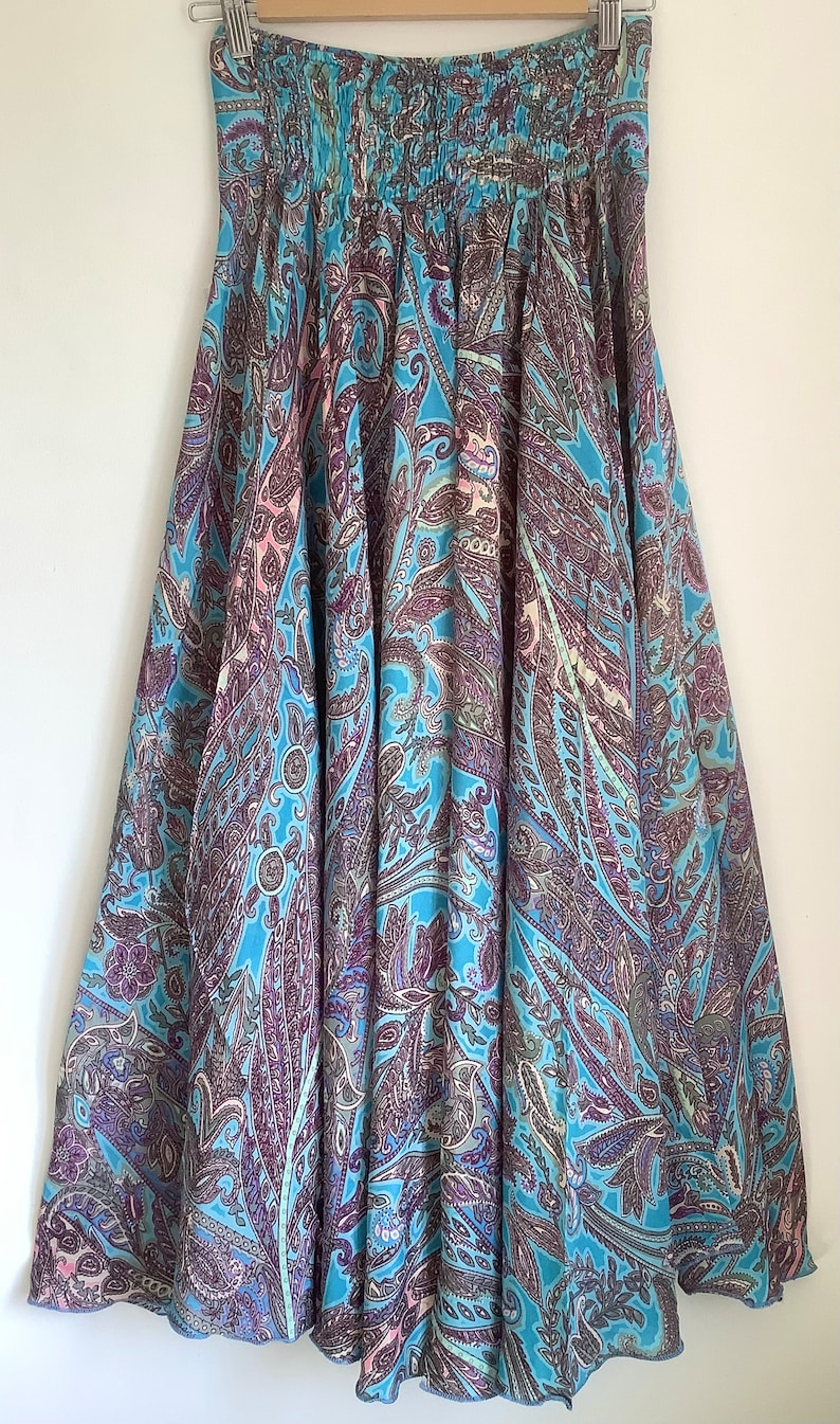 May include: A long, flowing skirt with a paisley print in shades of blue, purple, and pink. The skirt has a gathered waistband and a flowing silhouette.