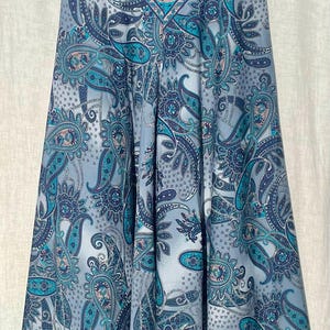 May include: A blue and gray paisley print skirt with a flared silhouette. The skirt has a high waist and a fitted waistband.