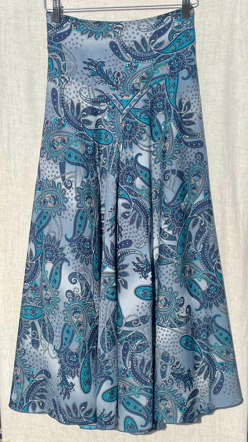 May include: A blue and gray paisley print skirt with a flared silhouette. The skirt has a high waist and a fitted waistband.