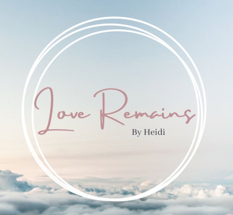 Puede incluir: Un c&iacute;rculo blanco con un doble contorno sobre un fondo de cielo nublado. El texto "Love Remains" en letra cursiva rosa est&aacute; centrado en el c&iacute;rculo. El texto "By Heidi" est&aacute; centrado debajo del c&iacute;rculo.