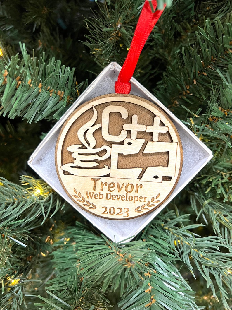 May include: A wooden Christmas ornament with a coffee cup and the text "C++" on it. The ornament also has the text "Trevor Web Developer 2023" on it.