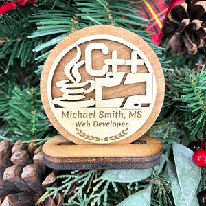 May include: A wooden ornament with a C++ logo, a coffee cup, and a laptop. The ornament also includes the text "Michael Smith, MS Web Developer" and a laurel wreath.