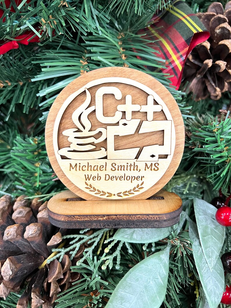 May include: A wooden ornament with a C++ logo, a coffee cup, and a laptop. The ornament also includes the text "Michael Smith, MS Web Developer" and a laurel wreath.