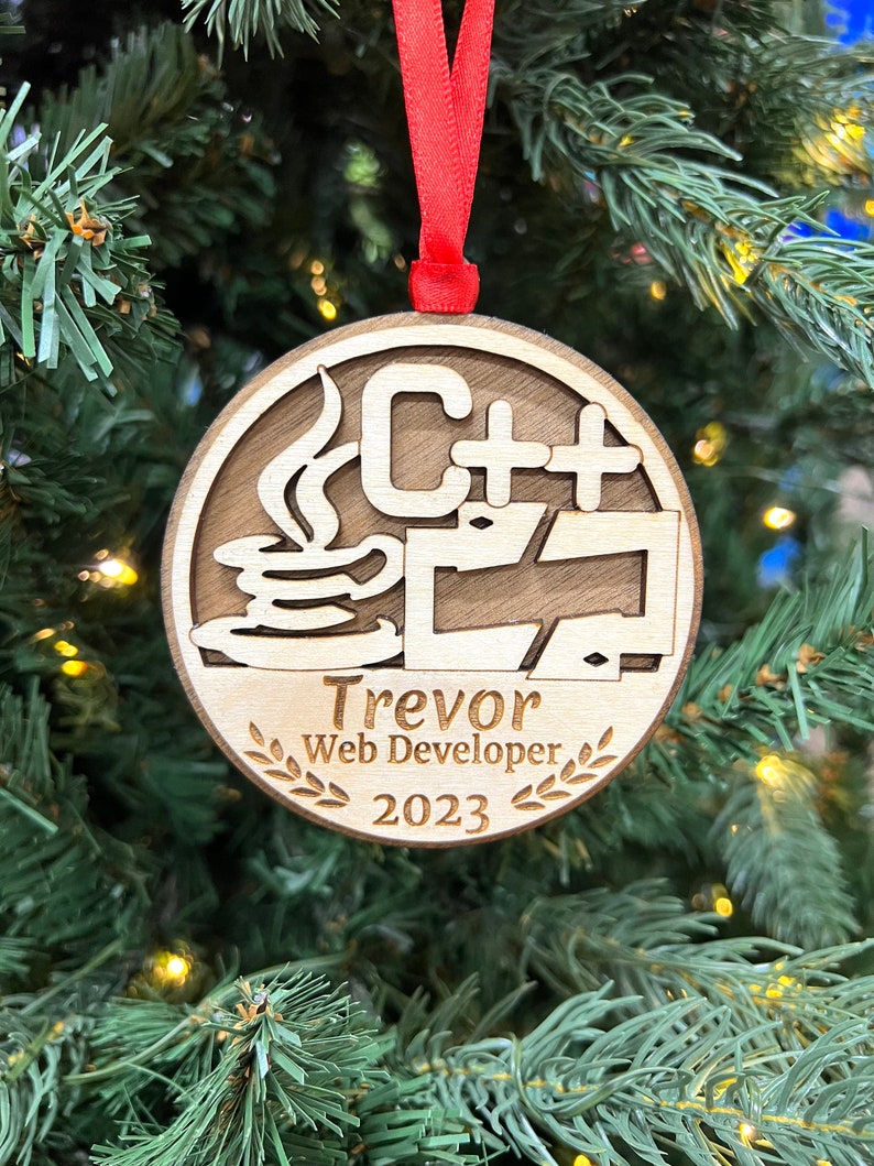 May include: A wooden Christmas ornament with a C++ logo, a coffee cup, and the text "Trevor Web Developer 2023".
