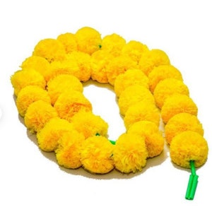 Puede incluir: Una larga guirnalda de pompones de flores de cal&eacute;ndula amarillas enhebradas con un hilo verde.