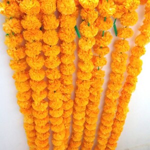 Puede incluir: Una guirnalda de flores de cal&eacute;ndula amarillas brillantes enhebradas. La guirnalda est&aacute; hecha de m&uacute;ltiples hebras de flores, cada hebra mide aproximadamente 90 cm de largo.
