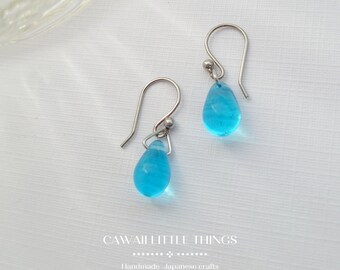 May include: A pair of silver teardrop earrings with light blue glass drops. The earrings are handmade Japanese crafts.