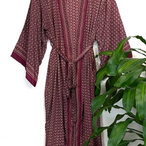May include: A long, burgundy robe with a paisley pattern and a matching sash. The robe has a  "Temple of Style" label.