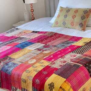 May include: A colourful patchwork quilt featuring a range of patterns and colours, including pink, yellow, blue, and brown. The quilt is made from kantha fabric and is ideal for adding a touch of bohemian style to any bedroom.