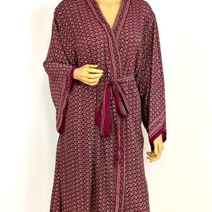 May include: A burgundy silk robe with a paisley pattern and a matching tie belt. The robe has long sleeves and a V-neck.