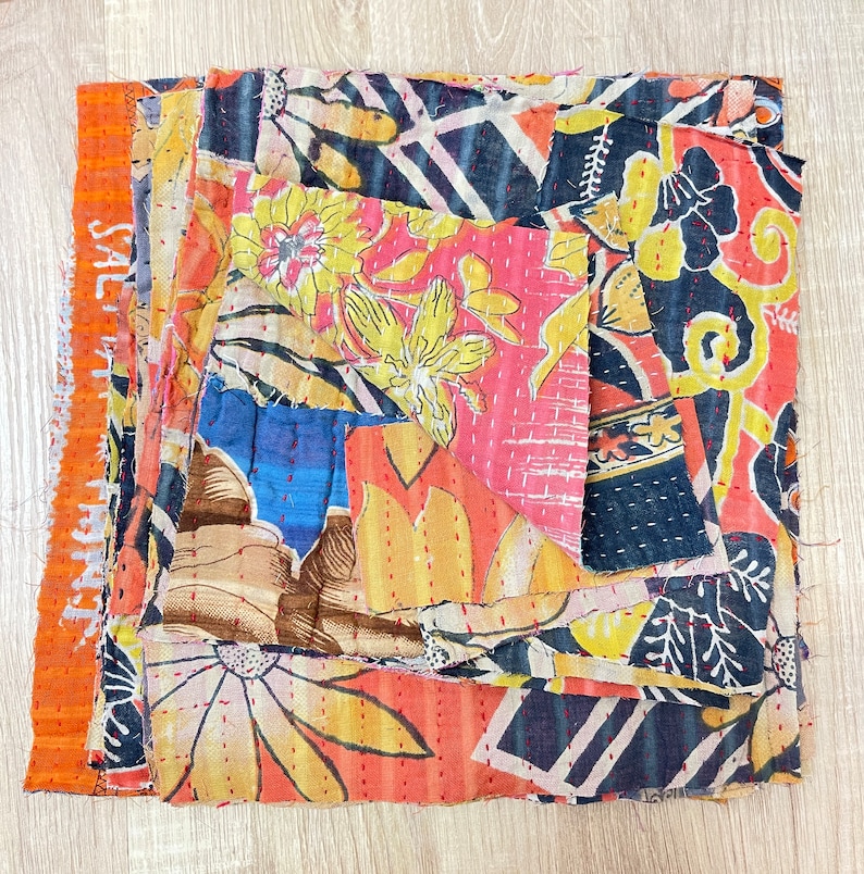 May include: A patchwork quilt made from colorful fabric scraps. The quilt is made up of different floral patterns in shades of orange, yellow, blue, and red. The quilt is hand-stitched and has a rustic, vintage look.