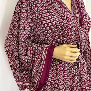 May include: A burgundy robe with a paisley pattern. The robe has long sleeves and a tie at the waist.