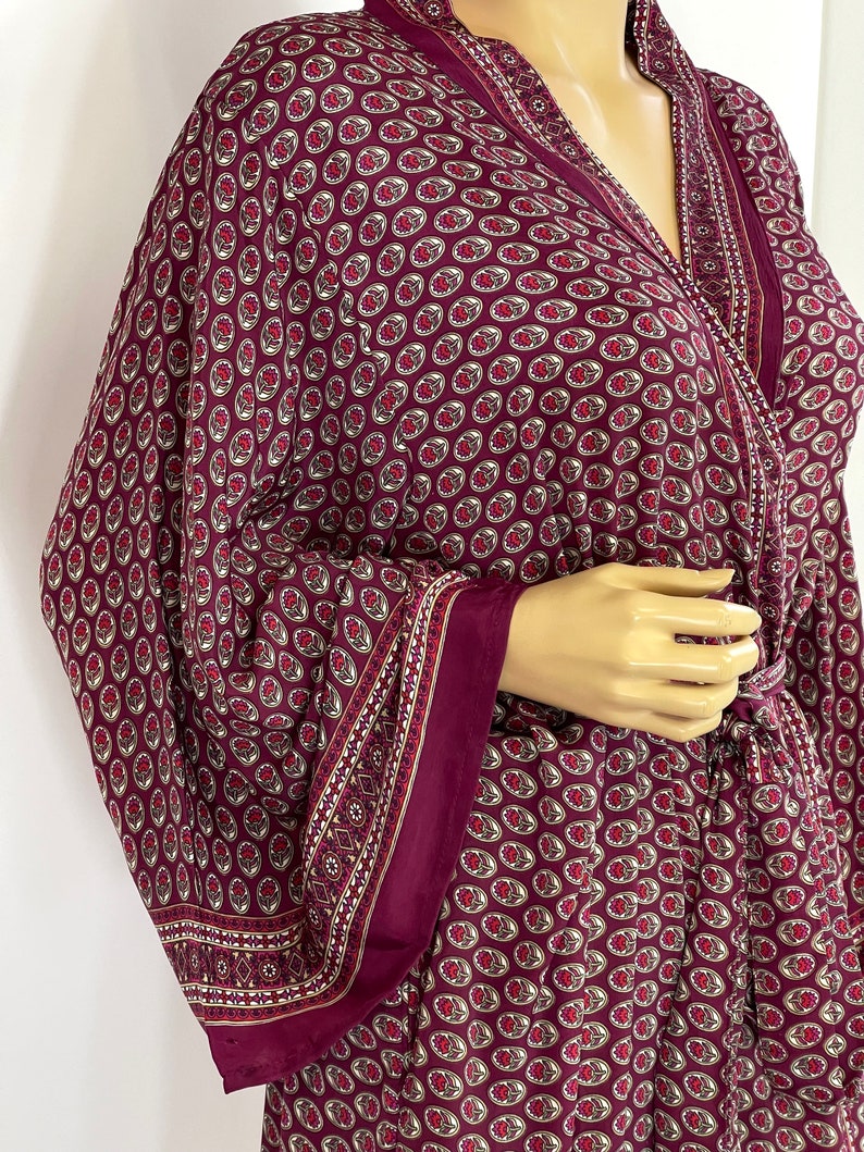 May include: A burgundy robe with a paisley pattern. The robe has long sleeves and a tie at the waist.