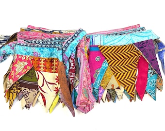May include: A colorful fabric garland with a variety of patterns and colors, including pink, blue, yellow, and green. The garland is made of triangular pieces of fabric sewn together.