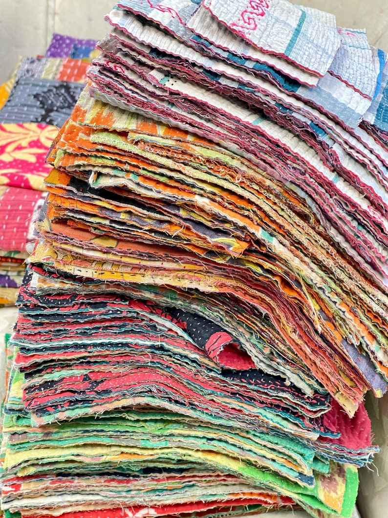May include: A stack of colorful fabric squares, each with a different pattern and texture. The squares are arranged in a staggered pattern, creating a visually appealing and textured display. The fabric squares are likely intended for quilting or other craft projects.