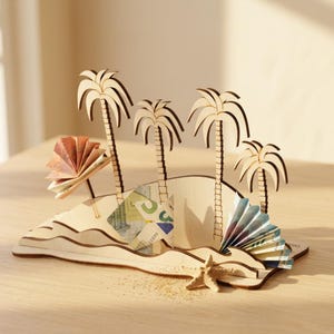 May include: A light-colored wooden island display featuring four laser-cut palm trees, a small starfish at the base, and layered wave-like structures. The display is decorated with folded paper currency tucked into the wooden slots and structures.