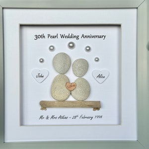 May include: A framed white background with two gray pebble figures representing a couple, with the words "John" and "Alice" on white hearts, and "Love" on a small brown heart. The text "30th Pearl Wedding Anniversary" and "Mr & Mrs Atkins - 28th February 1994" are also included.