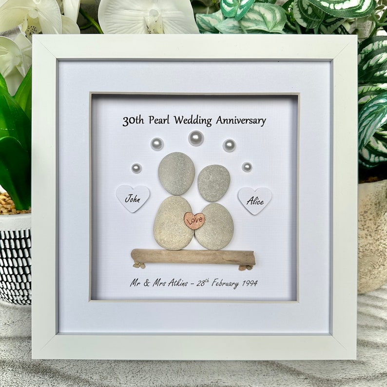 May include: White framed picture with a 30th Pearl Wedding Anniversary message. The picture features a pebble art couple with the names John and Alice, a heart with the word "Love" and the date February 28th, 1994.