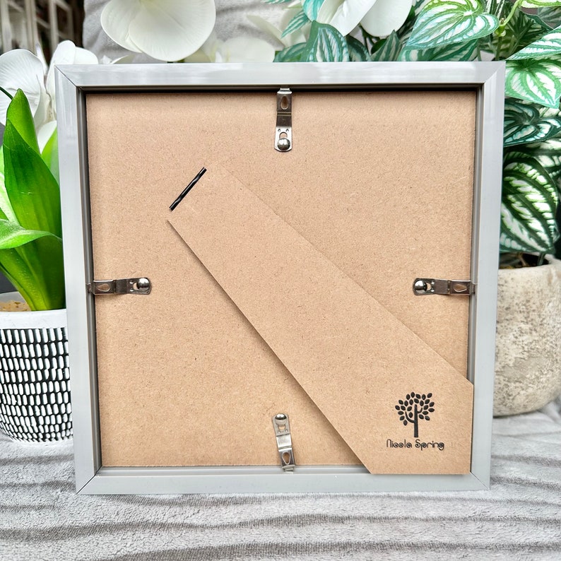 May include: A gray picture frame with a brown backing and a small tree logo that says "Nicola Spring".