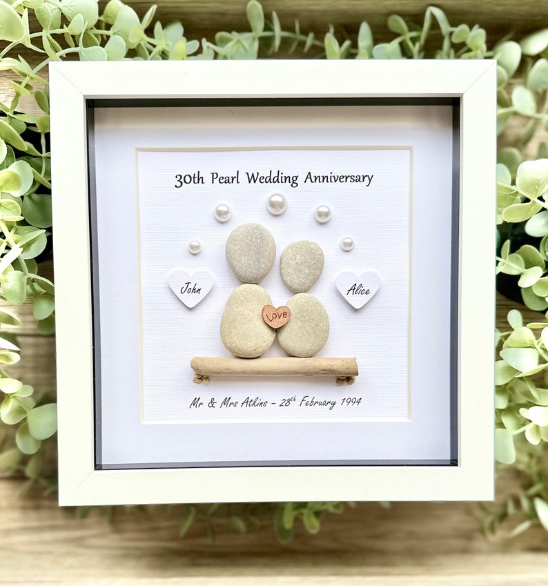 May include: A white framed picture with a 30th Pearl Wedding Anniversary message. The picture features a pebble art couple with the names John and Alice, a heart with the word "Love" and the date February 28, 1994.