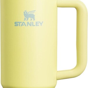 Puede incluir: Vaso Stanley amarillo p&aacute;lido con asa y pajita transparente. El vaso tiene tapa blanca y banda plateada. El logotipo de Stanley est&aacute; impreso en azul claro. Este termo de viaje est&aacute; dise&ntilde;ado para mantener las bebidas fr&iacute;as.