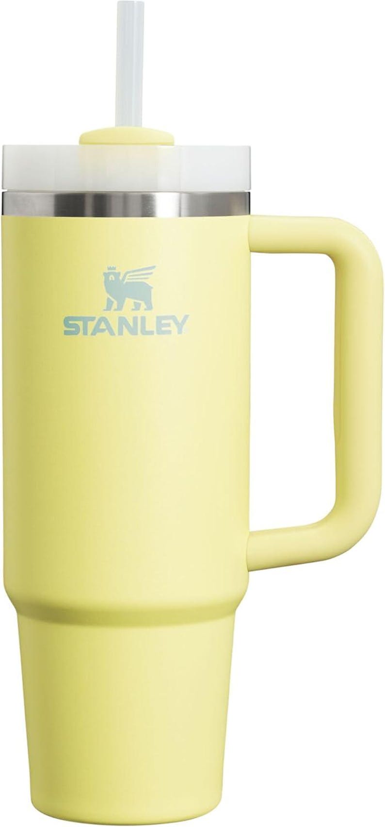 Puede incluir: Vaso Stanley amarillo p&aacute;lido con asa y pajita transparente. El vaso tiene tapa blanca y banda plateada. El logotipo de Stanley est&aacute; impreso en azul claro. Este termo de viaje est&aacute; dise&ntilde;ado para mantener las bebidas fr&iacute;as.