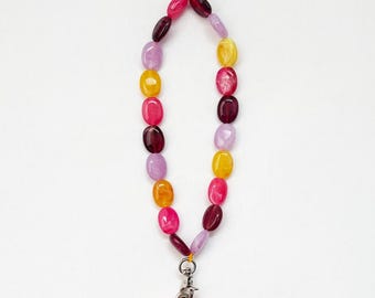 May include: A colorful phone charm made of oval-shaped beads in shades of purple, pink, yellow, and red. The charm is attached to a silver swivel clip.