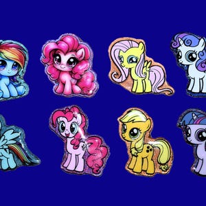 May include: A collection of eight small, glittery, cartoon-style pony figures arranged in two rows. The ponies feature vibrant colors including blue, pink, yellow, and purple, with large expressive eyes and distinct manes and tails.
