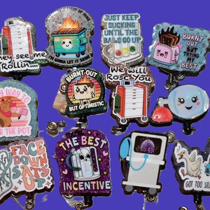 K&ouml;nnte beinhalten: Eine Sammlung von glitzernden Ausweisrollen im Cartoon-Stil mit verschiedenen Designs und Phrasen. Die Designs umfassen einen brennenden M&uuml;llcontainer, einen Toaster und medizinische Ger&auml;te. Texte sind "They see me rollin", "Burnt out but optimistic" und "The best incentive".