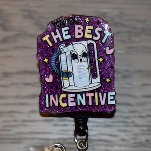 K&ouml;nnte beinhalten: Ein lila Glitzer-Ausweisrolle mit dem Text "YOU'RE THE BEST INCENTIVE". Die Ausweisrolle zeigt ein Cartoon-Bild eines medizinischen Ger&auml;ts. Das Design umfasst Herzen und Sterne.