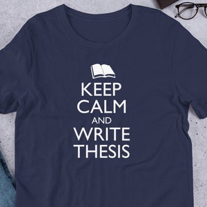 May include: A navy blue t-shirt with white text that reads "Keep Calm and Write Thesis" with an open book icon above the text.