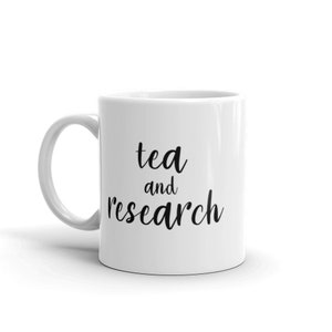 May include: White ceramic mug with black text that reads "tea and research".